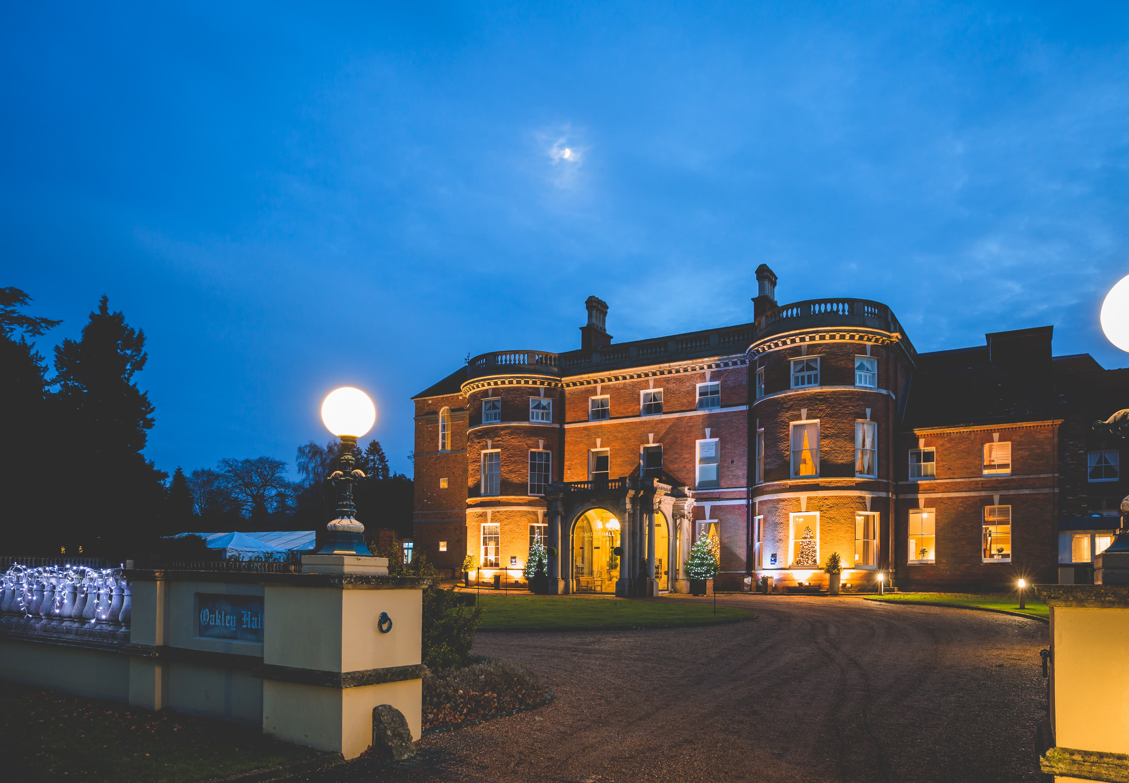 A photograph of the external of Oakley Hall Hotel at dusk.